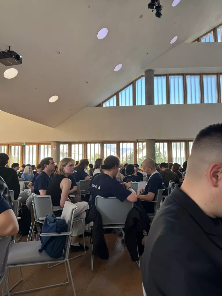 Зал на Skoltech Innovation Workshop — высокие потолки, длинные ряды столов, ноутбуки, участники слушают лекцию